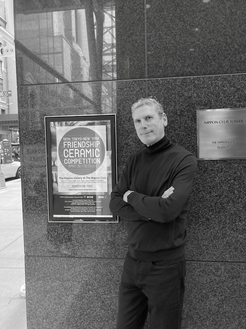 Christopher Flach beside the poster for the 19th Tokyo-New York Friendship Ceramic Competition at The Nippon Gallery, New York, 2023